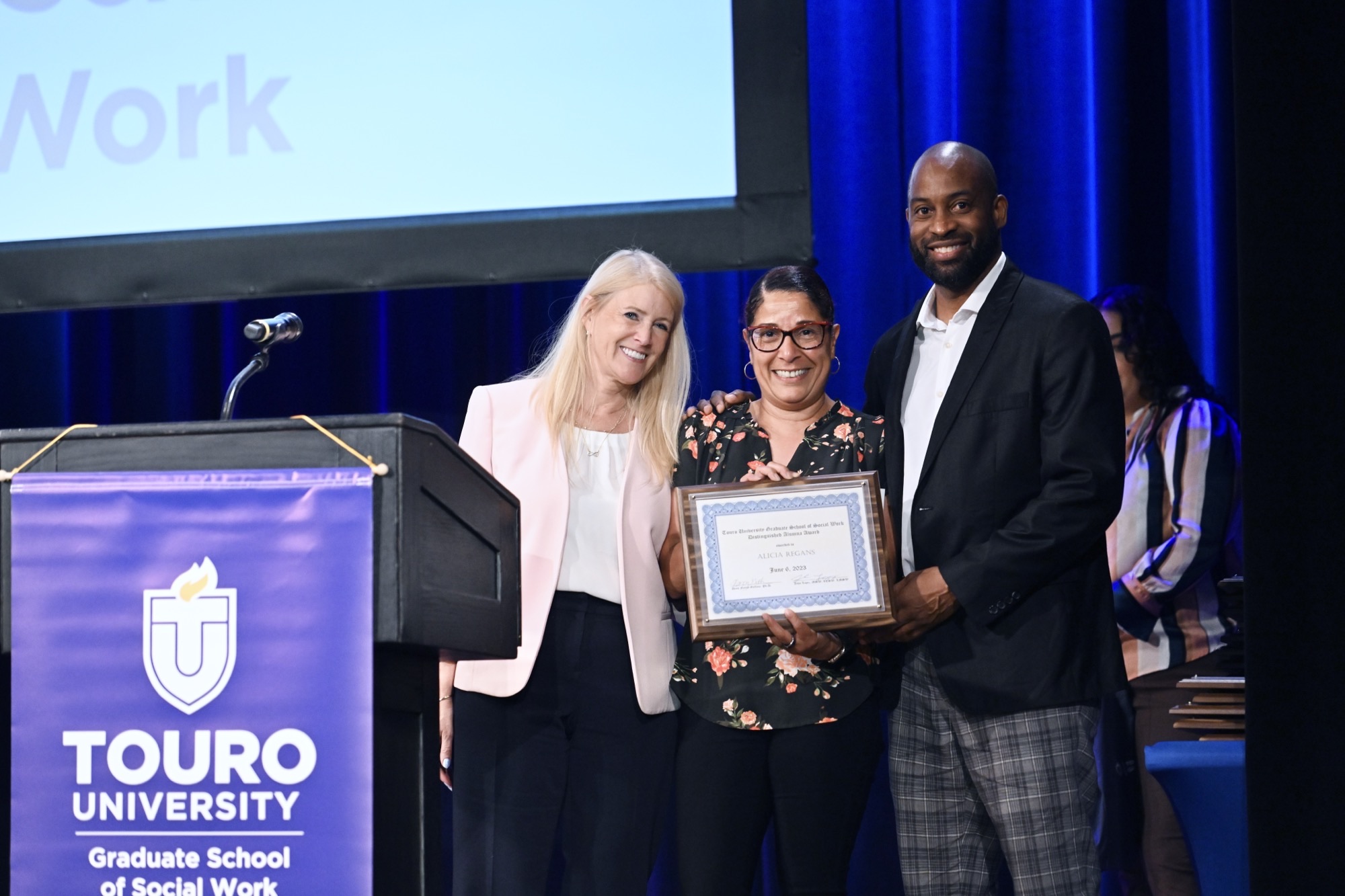 Alumna Alicia Regan, Class of ‘15, holding her Alumna of the Year Award next to GSSW Dean Nancy Gallina and GSSW Alumni Association President John Lopez