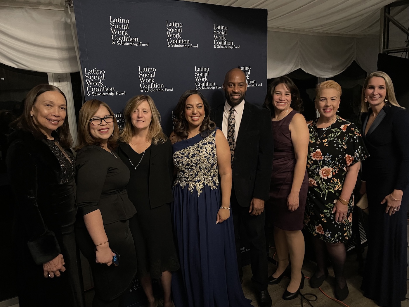 Men and women, Touro administration, faculty, alumnus and student lined up smiling at camera after receiving award. 