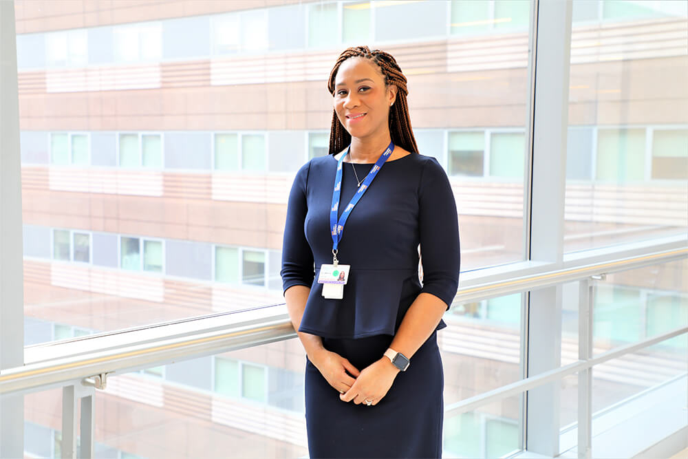 Latoya Delmadge, standing next to a large window in an office